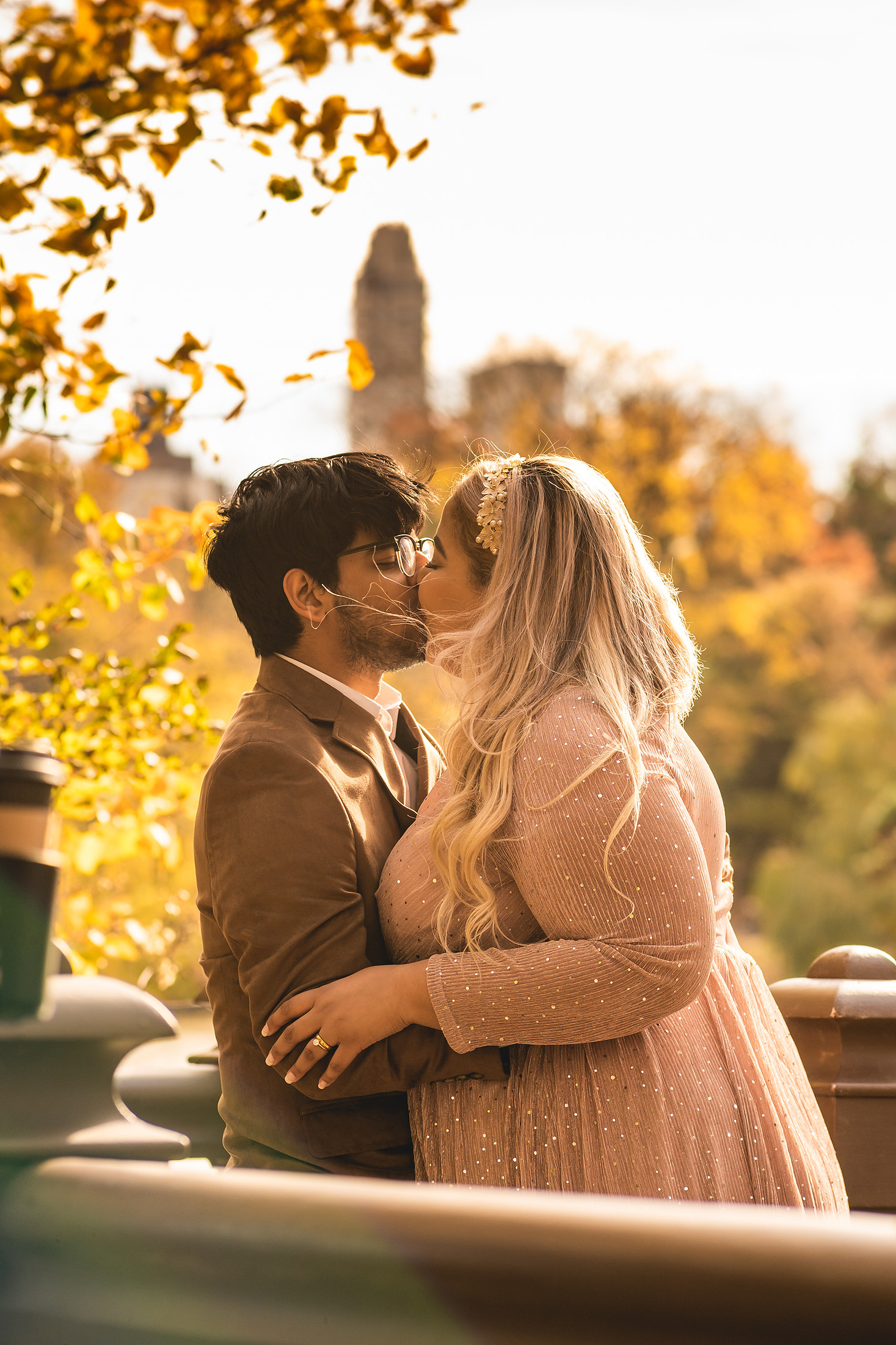 A couple kissing beneath golden autumn leaves