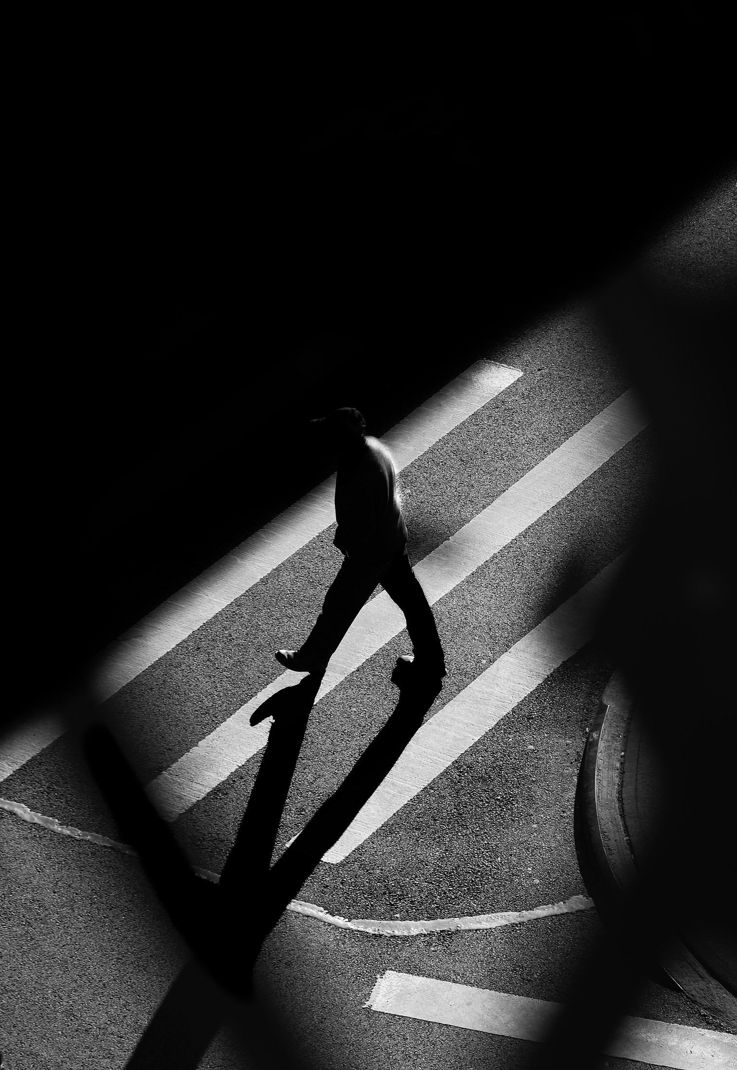 Silhouette of a pedestrian on the crosswalk, long shadow, black and white